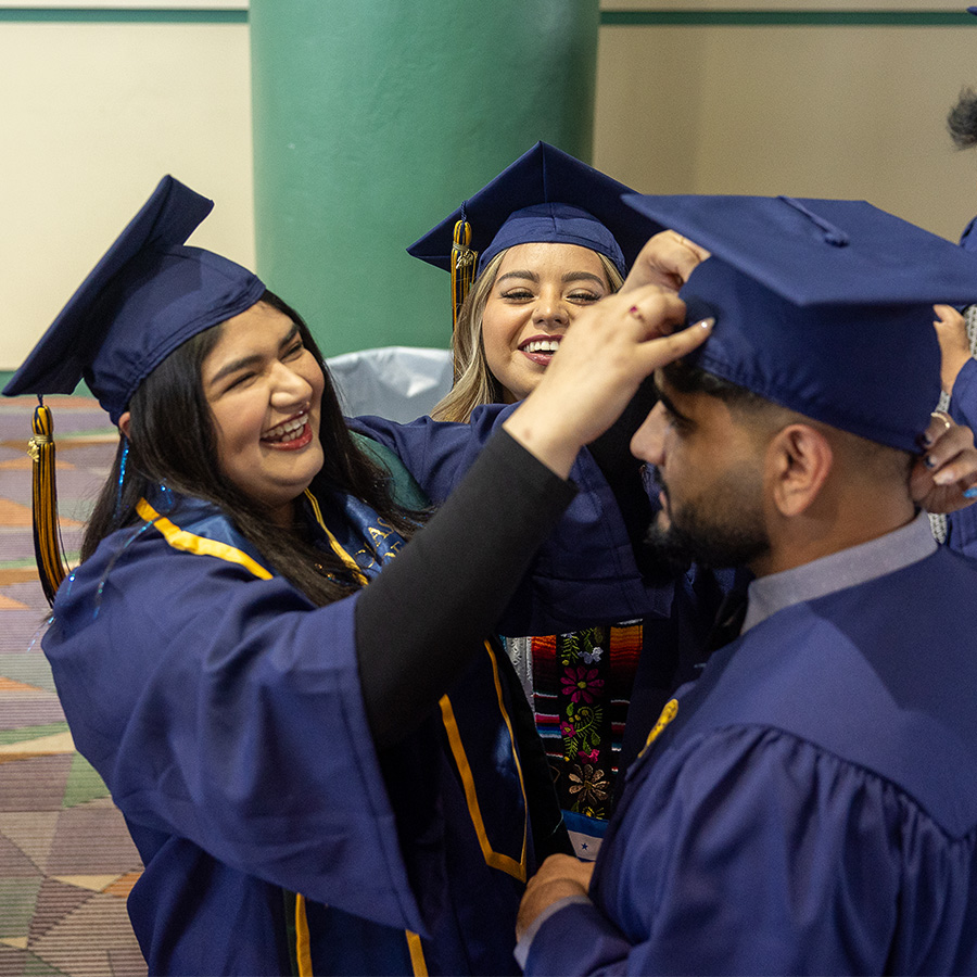 A UNCG student adjusts a graduate's cap.
