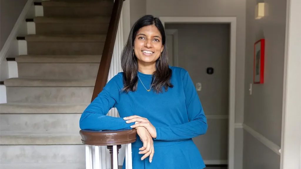 UNCG alumna Ruhani Amin leans against the stairway bannister.