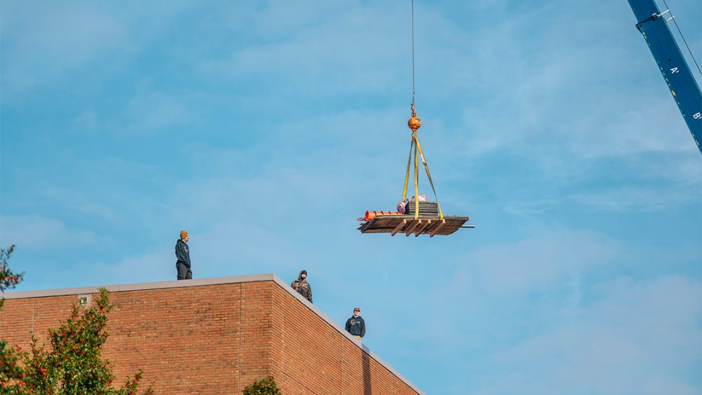 Workers install solar panels on UNCG Middle College roof.