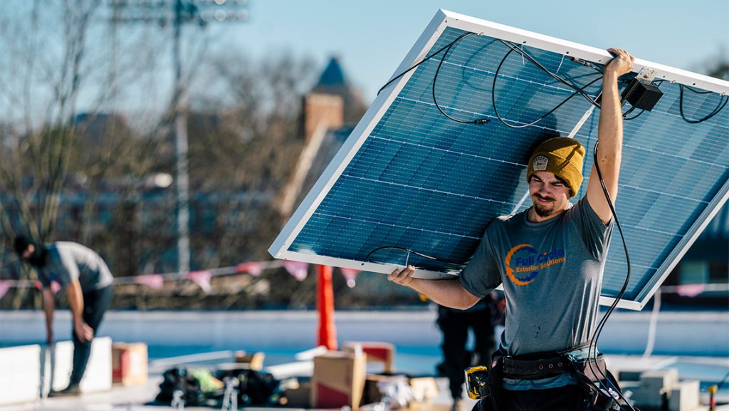Workers install solar panels on UNCG Middle College roof.