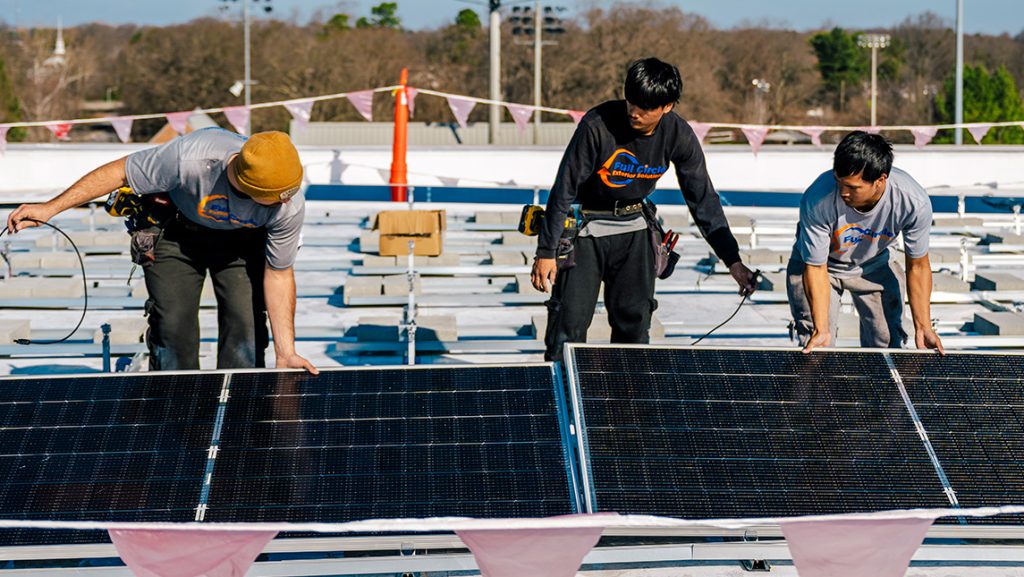 Workers install solar panels on UNCG Middle College roof.