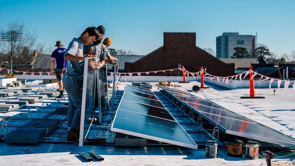 Workers install solar panels on UNCG Middle College roof.