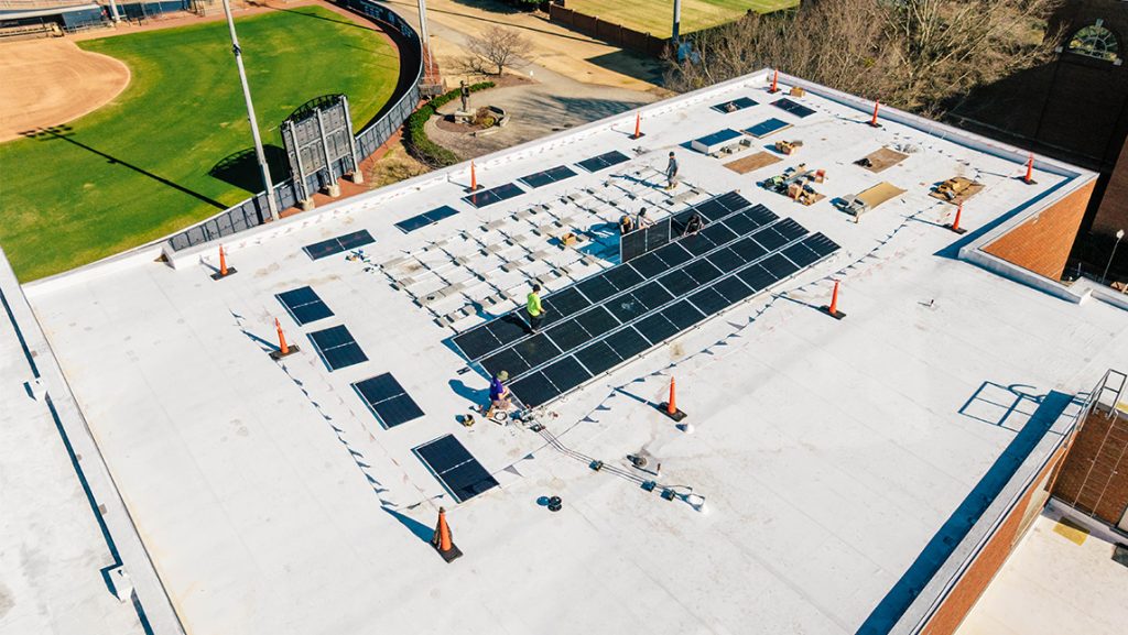 Workers install solar panels on UNCG Middle College roof.