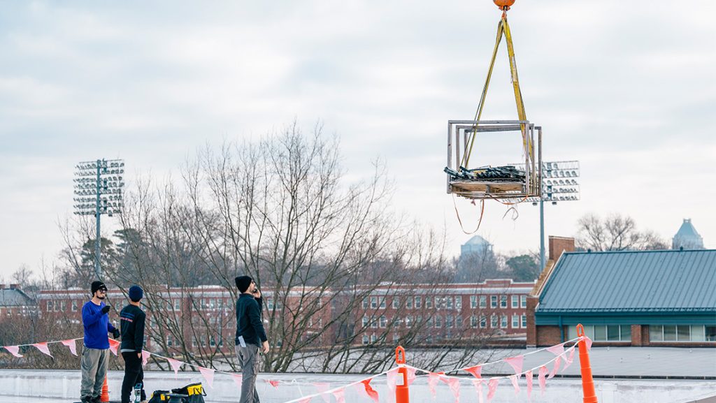 Workers install solar panels on UNCG Middle College roof.