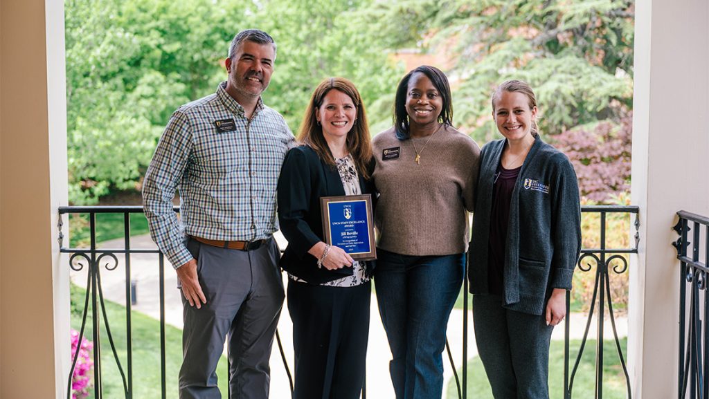 Four UNCG staff members and friends show off an award.