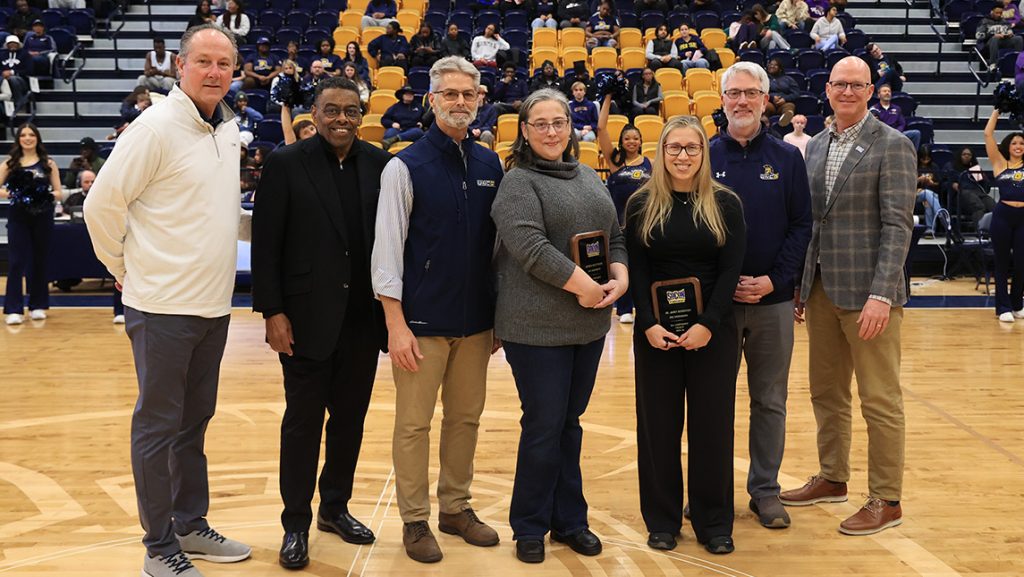 UNCG faculty/staff Janet Boseovski and Jessica Quattrucci hold awards on the basketball court.