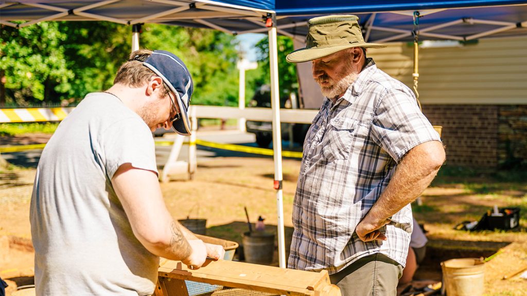 UNCG lecturer Geoffrey Hughes with a student at an Old Salem dig site.