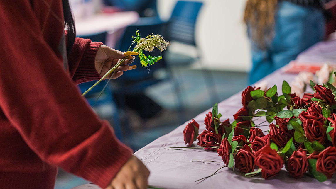 Close-up on hands gathering roses and other flowers.