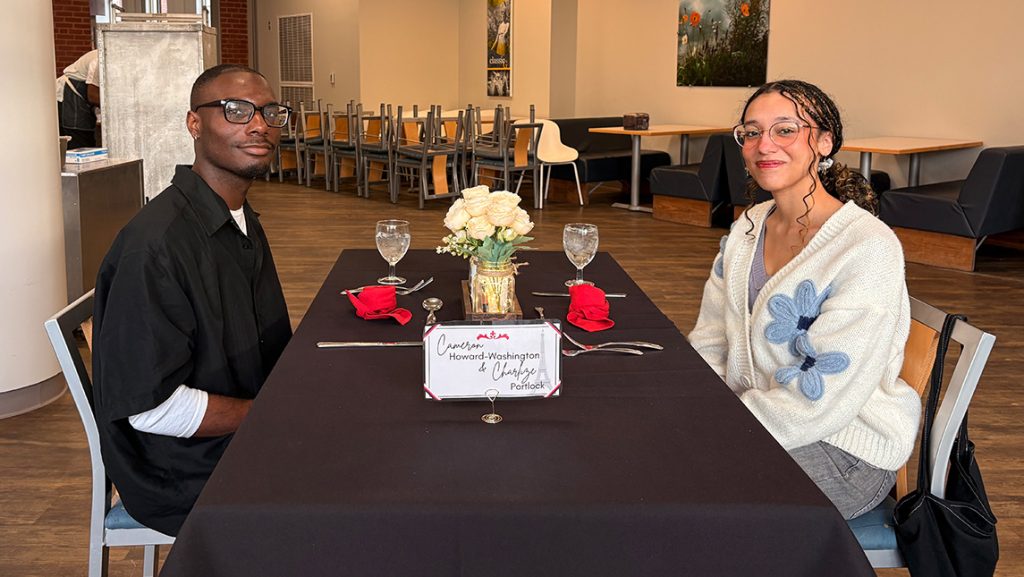 Students sit together at a table with flowers and tablecloth.