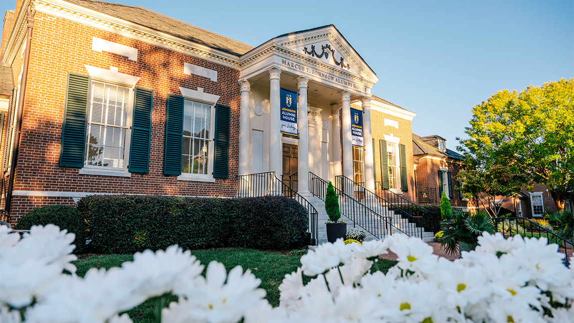UNCG's Marcus T. Johnson Alumni House with daisies growing outside.
