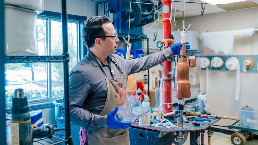 Man in apron in a workshop making molds of prosthetic limbs.