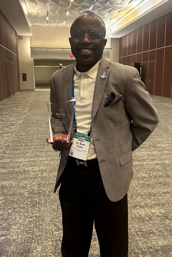 UNCG's Dean of Students Brett Carter holds an award.