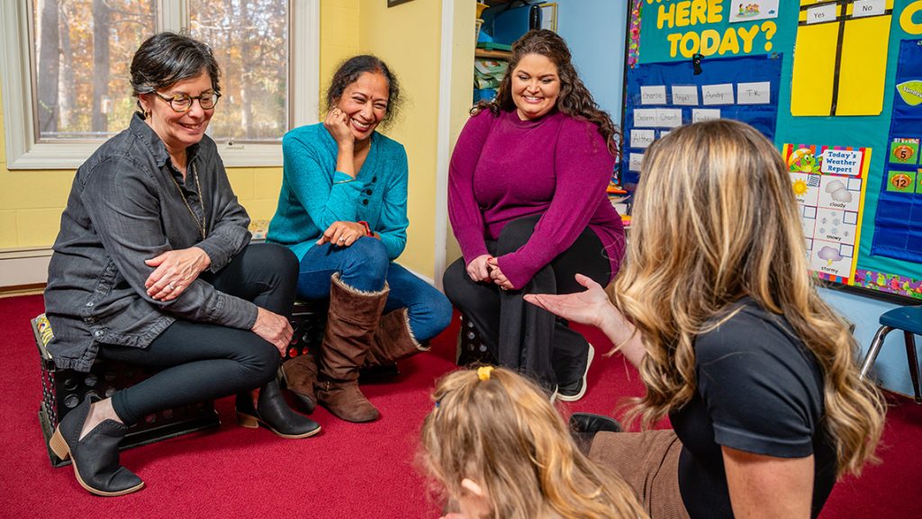UNCG CYFCP staff work with a preschool teacher and student.