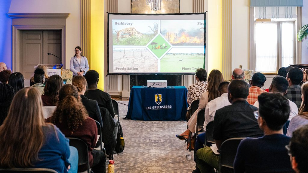 A UNCG student gives a PowerPoint presentation inside Johnson Alumni House.