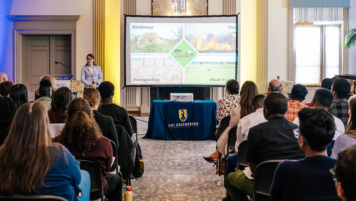 A UNCG student gives a PowerPoint presentation inside Johnson Alumni House.
