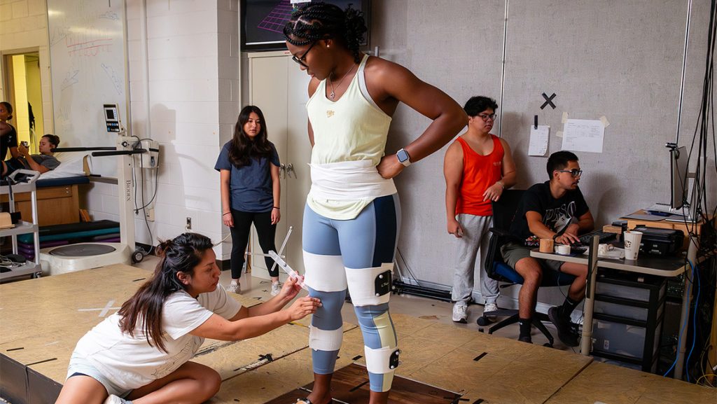 A UNCG kinesiology study puts physiology measuring probes on another student.