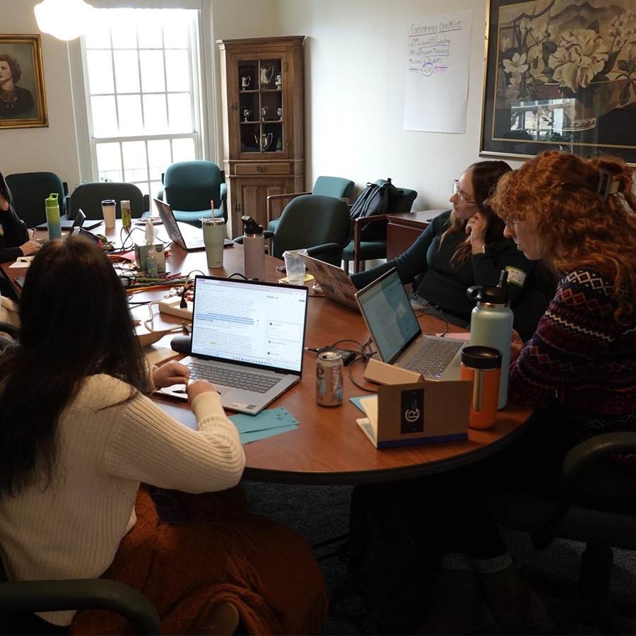 A group of UNCG students around a table writing an academic paper.