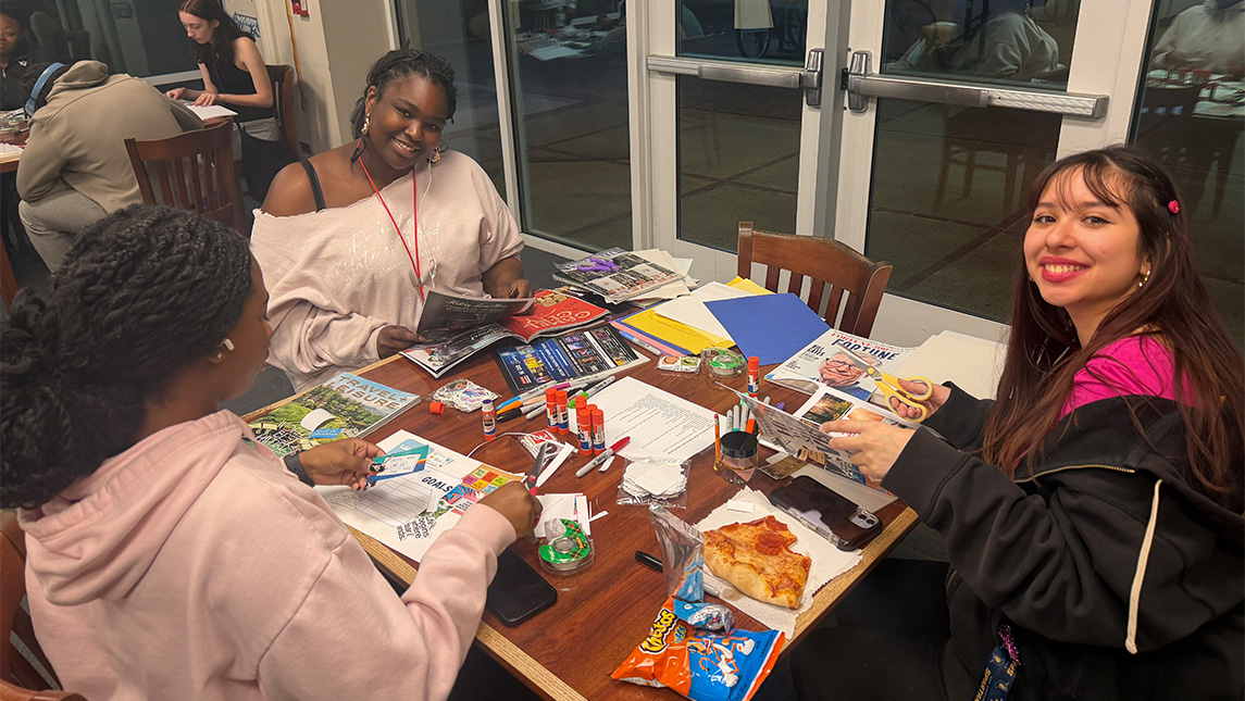 UNCG students around a table doing activities.