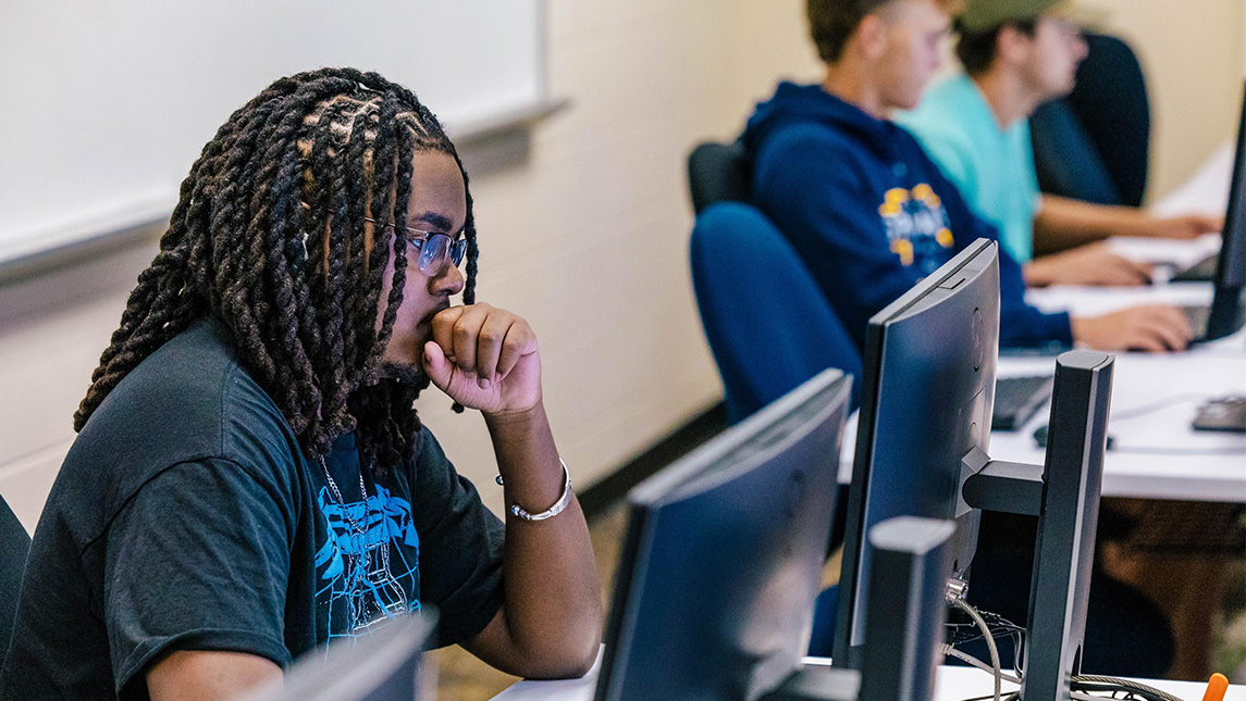UNCG students concentrating while looking at computers.
