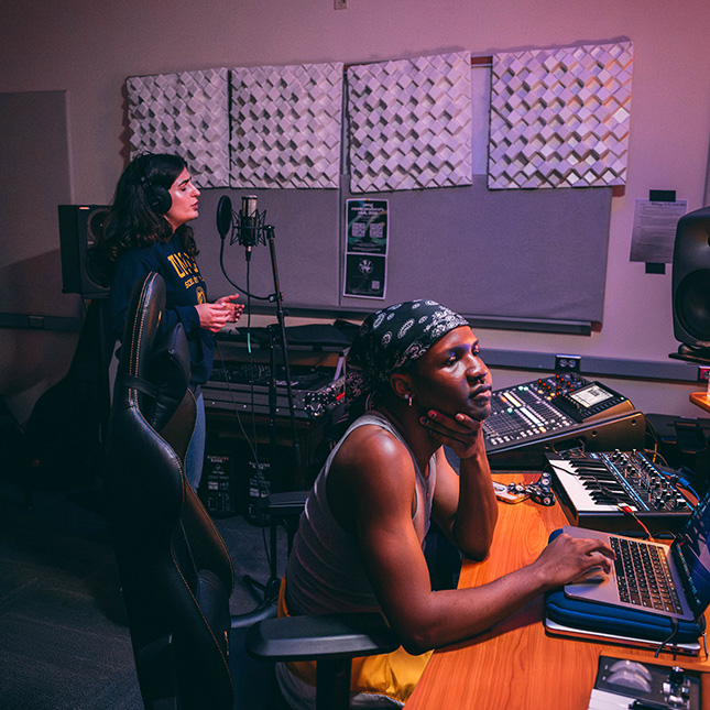 Two students work in a music studio.