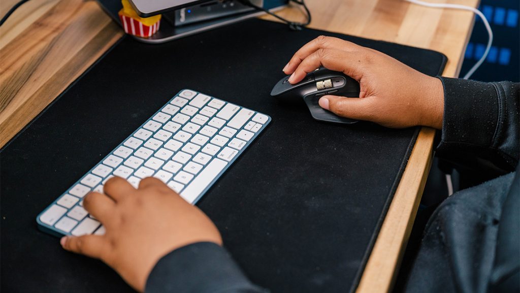 Close-up on hands using a keyboard and mouse.
