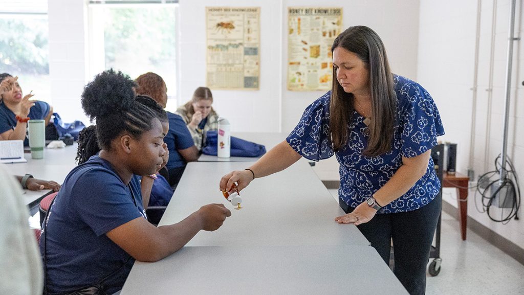 Dr. Kaira Wagoner holds out an experiment to a student.