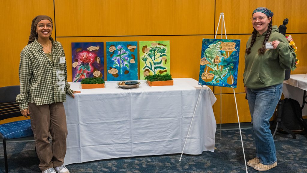 Aminah Coppage and Mallory Cox-Shreffler next to their artwork and ceramics.