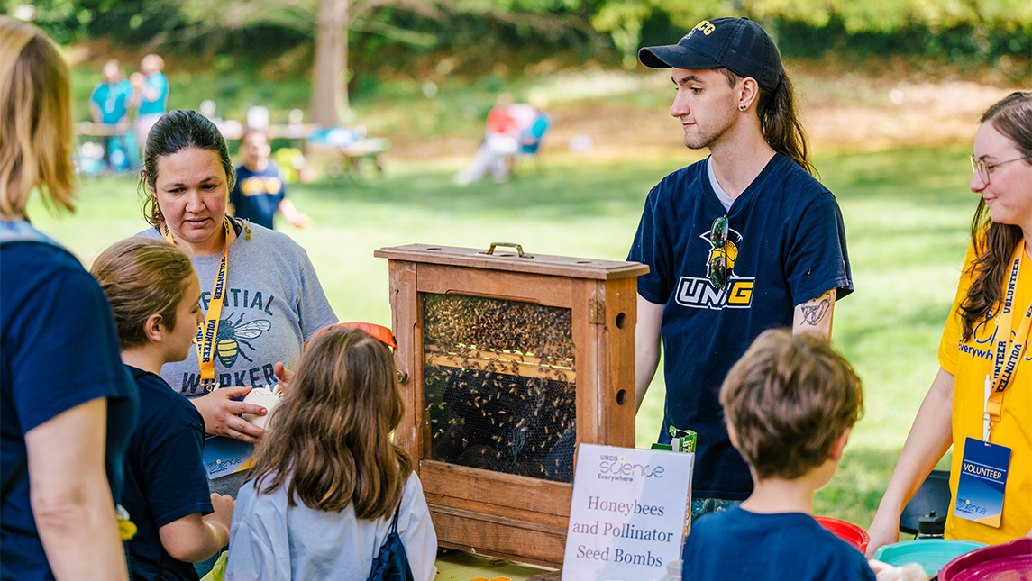 Dr. Kaira Wagoner shows a small beehive to children.