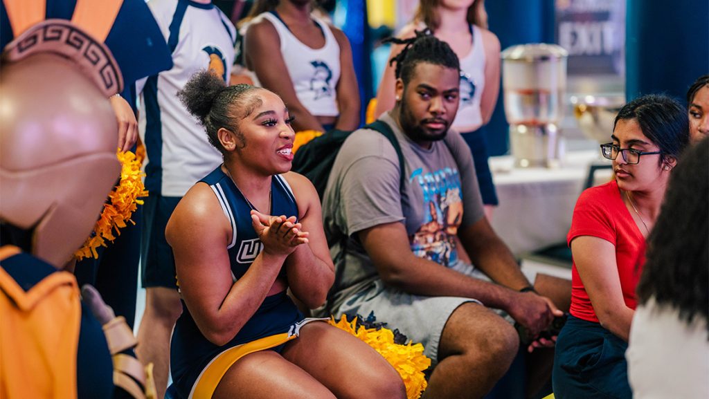 David Sandy sits in a group with a UNCG cheerleader and mascot Spiro.