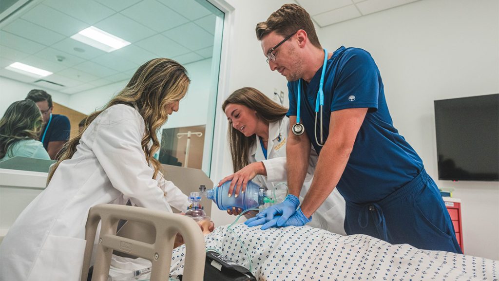 Huong Thuy Ka’24, Lyndsey Dark ’24, and Zack Wiggins ’25, conduct nursing with a manikin in a hospital bed.