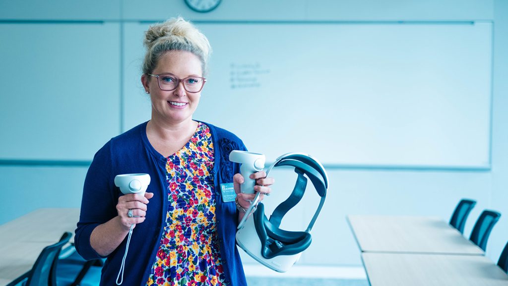 UNCG's Dr. Lindsay Draper holds a virtual reality headset.