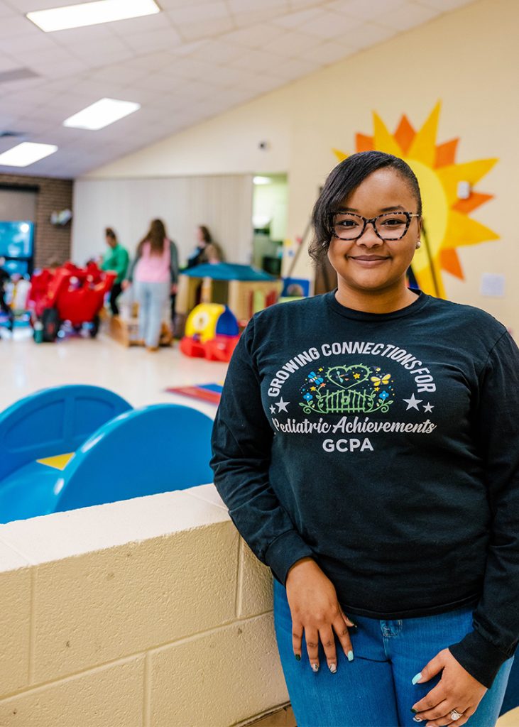 UNCG alumna Ma'Kayla Jefcoat stands inside playroom of Growing Connections for Pediatric Achievements.