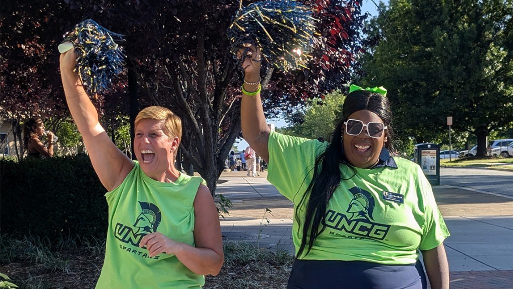 UNCG staff wave pompoms.