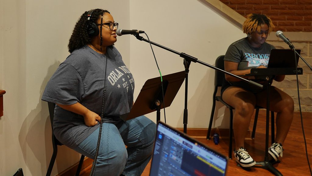 UNCG students singing in front of mics.