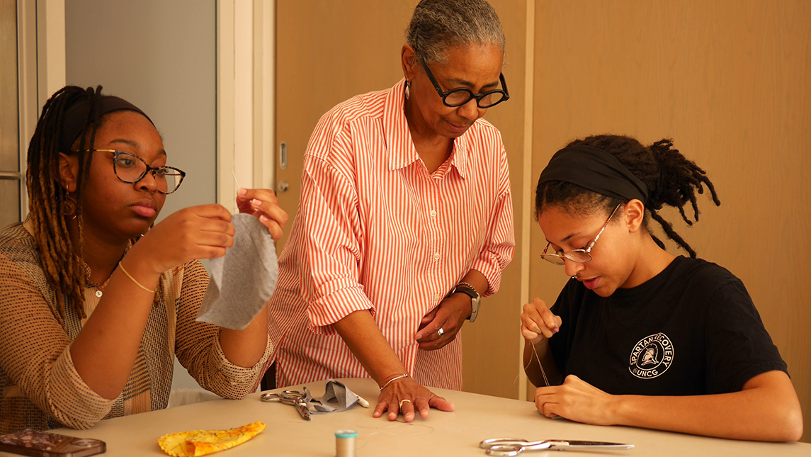 Precious D. Lovell watches UNCG students sew.