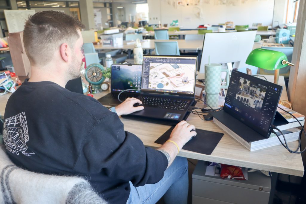 Jason Rich sits at his desk space in Gateway Studios, working design concepts on his laptop.