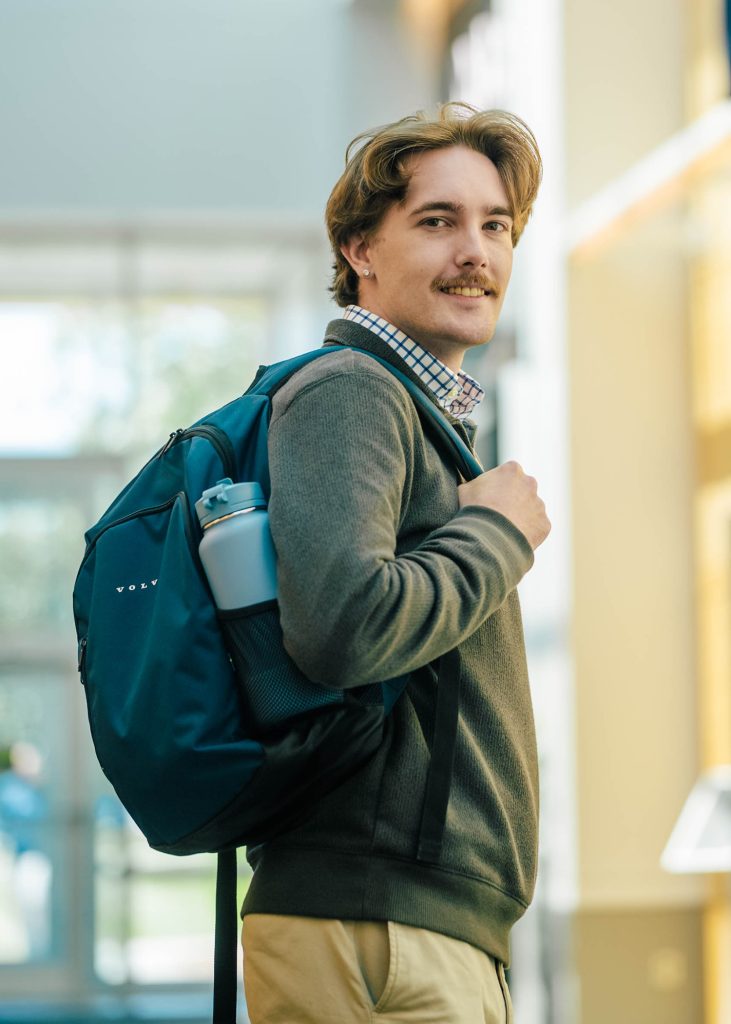 Student with a backpack looks over his shoulder in an atrium.