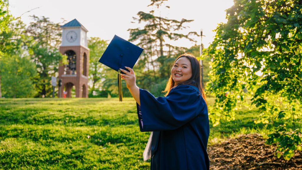 a woman in a cap and gown by the bell tower