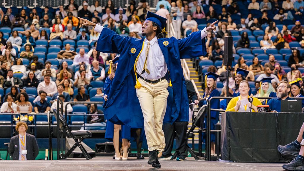 UNCG graduate Christian Bartney poses on the Commencement stage.