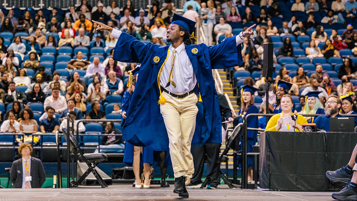 UNCG graduate Christian Bartney poses on the Commencement stage.