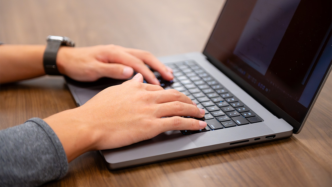 Close-up on hands typing on a laptop.