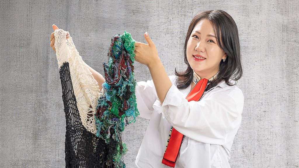 Dr. Grace Bang holds up a knitted garment.