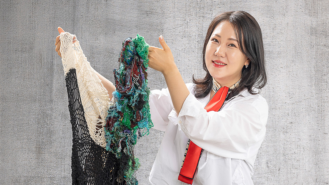 Dr. Grace Bang holds up a knitted garment.