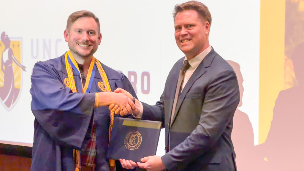 Jason Rich receives his diploma from Interior Architecture Department Head Travis Hicks at the program recognition ceremony.