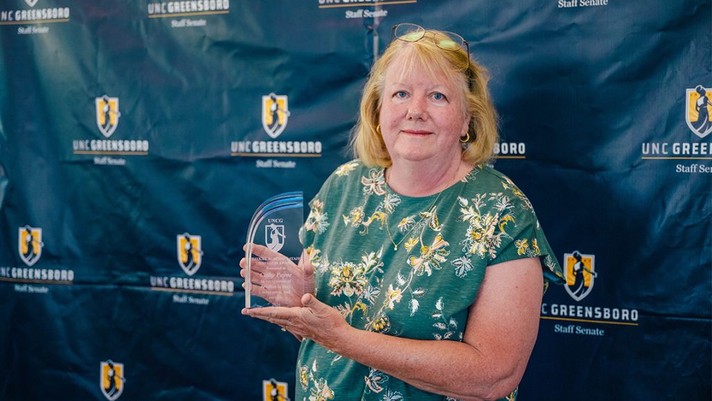 Cathy Payne holds an award.