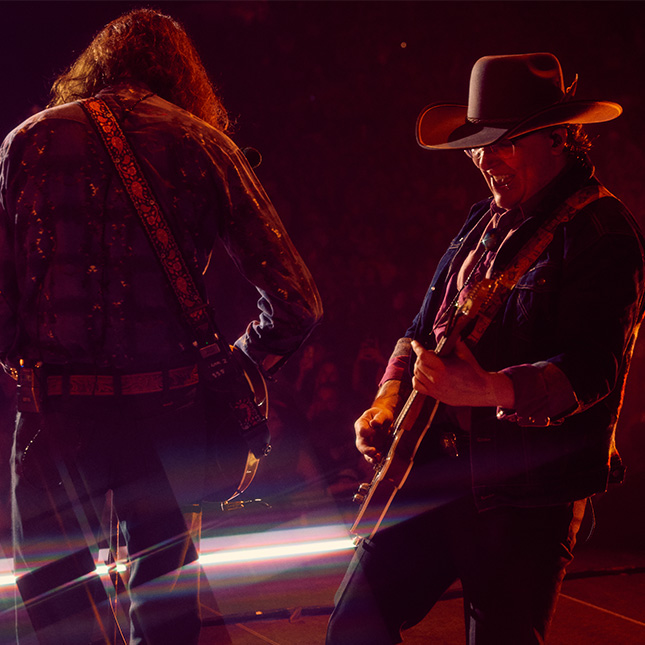 Two guitarists play together on stage.
