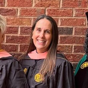 Susanna Barton in her UNCG graduation gown with three gerontology faculty members.