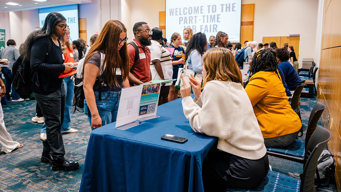 UNCG students talk to job recruiters at a table.