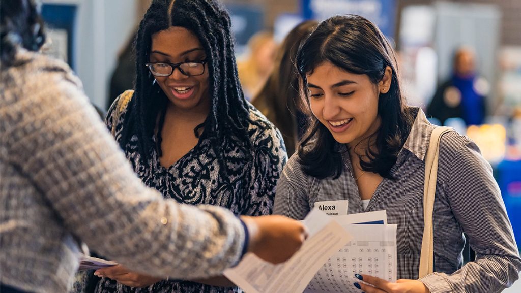 Two UNCG students share resumes with a job recruiter.