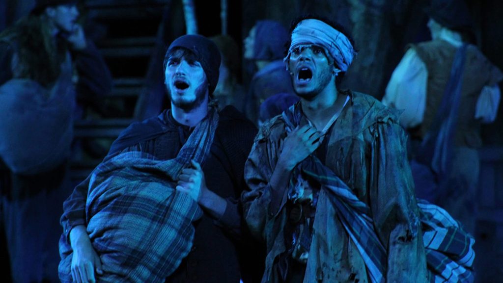 Actors wearing bedraggled colonial attire.